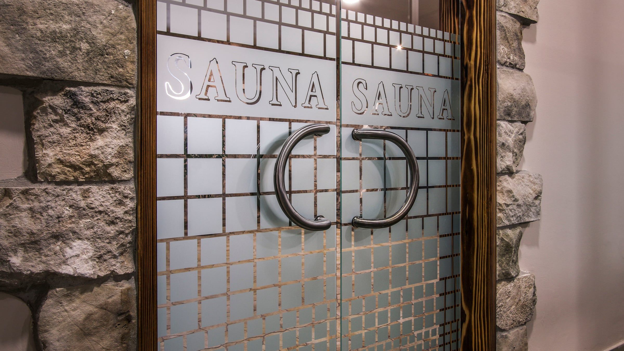 Staklena vrata saune s natpisom Sauna
